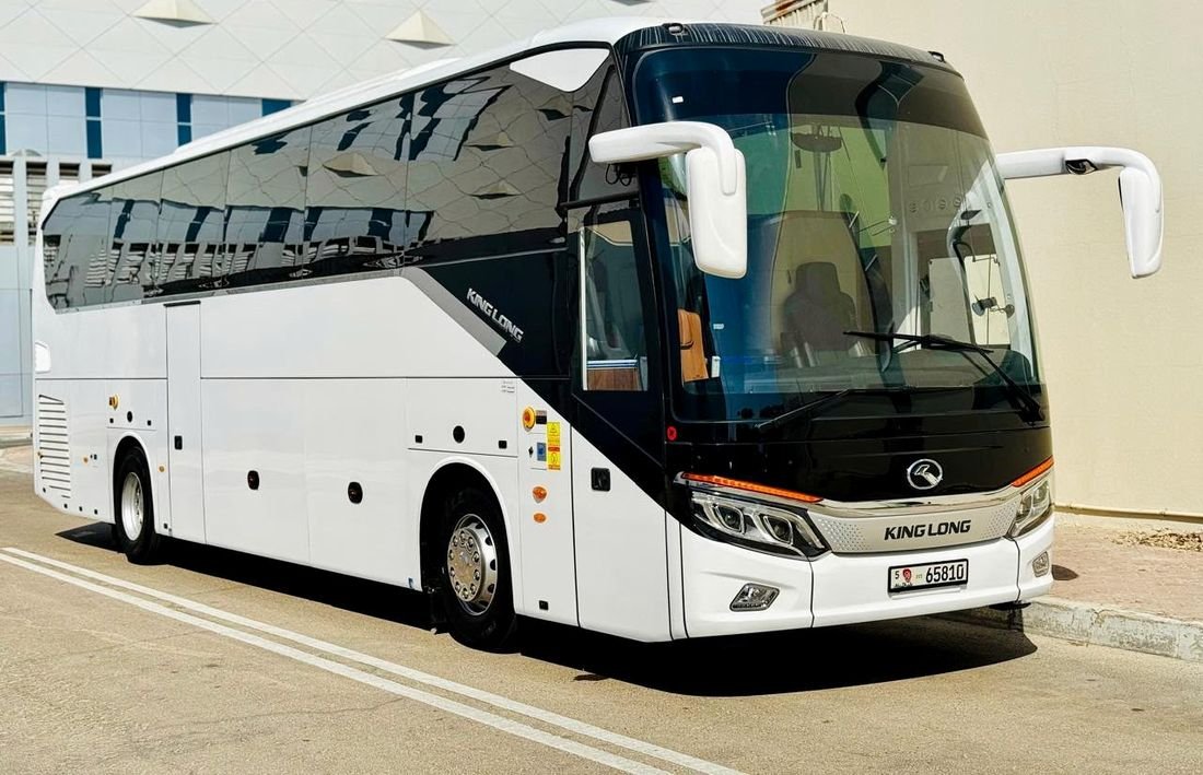 White 50-seat coach parked outside a building in the sun