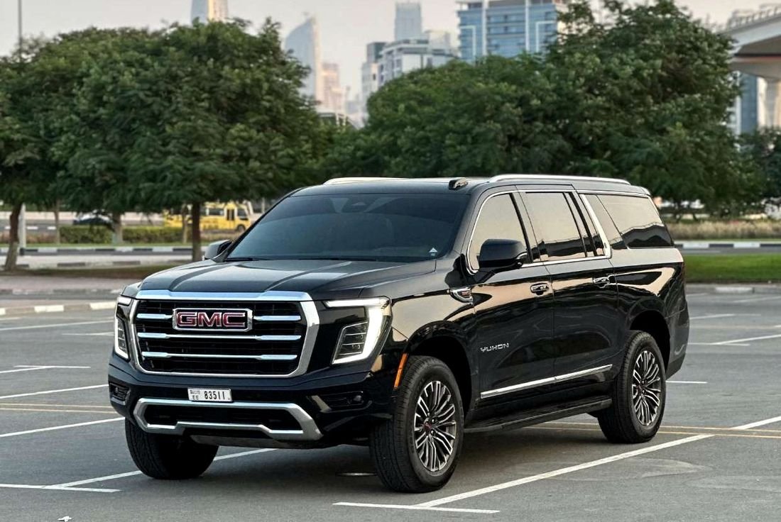 Black GMC Yukon parked with the Dubai skyline behind