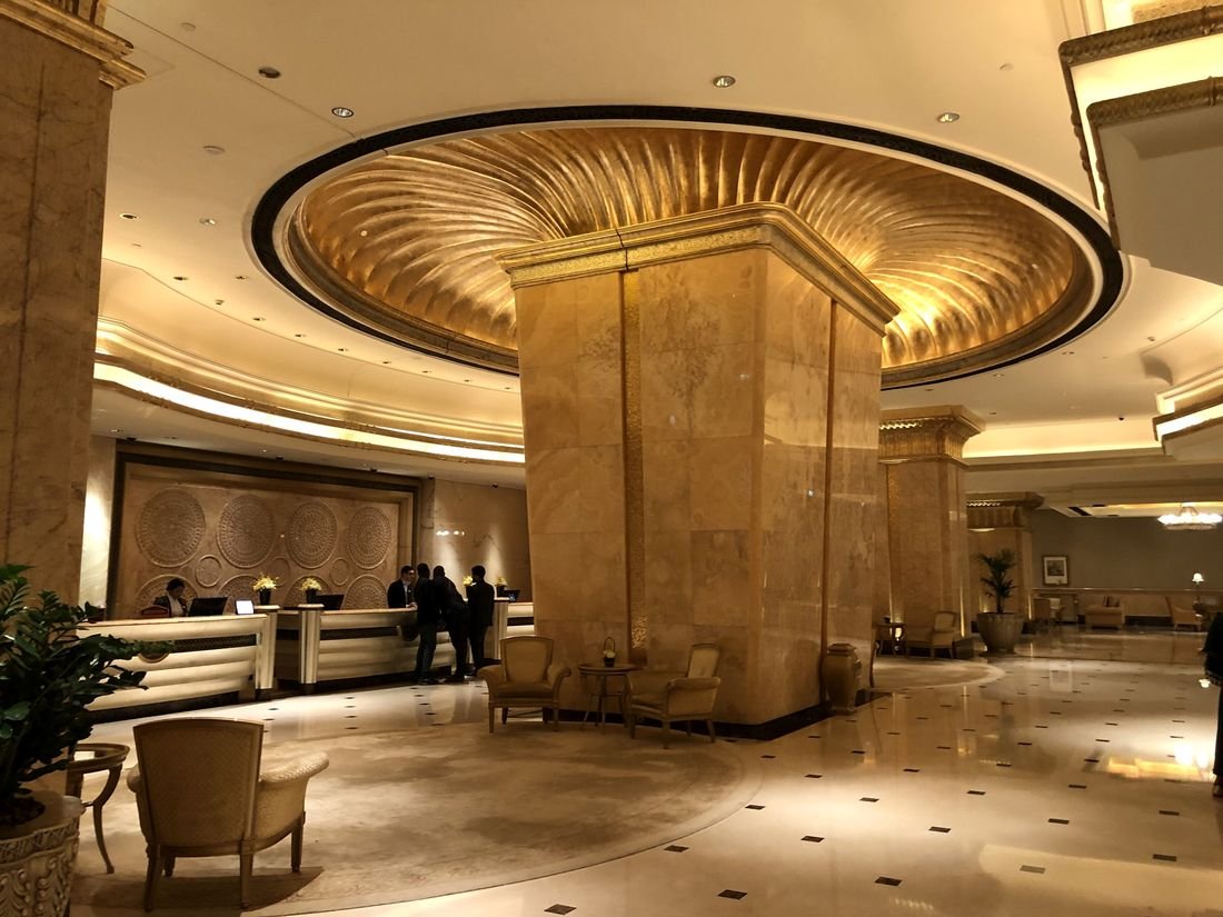 A grand hotel lobby with marble columns and a gilded domed ceiling