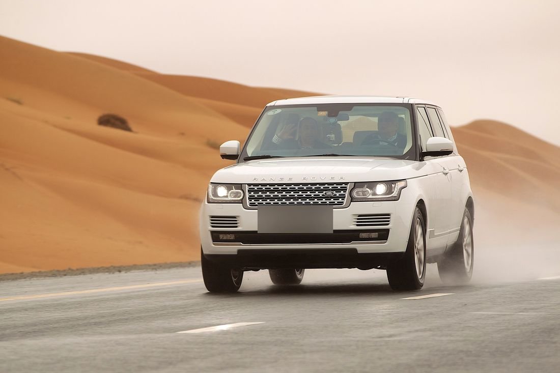 Luxury SUV on a desert road with mountains in the distance