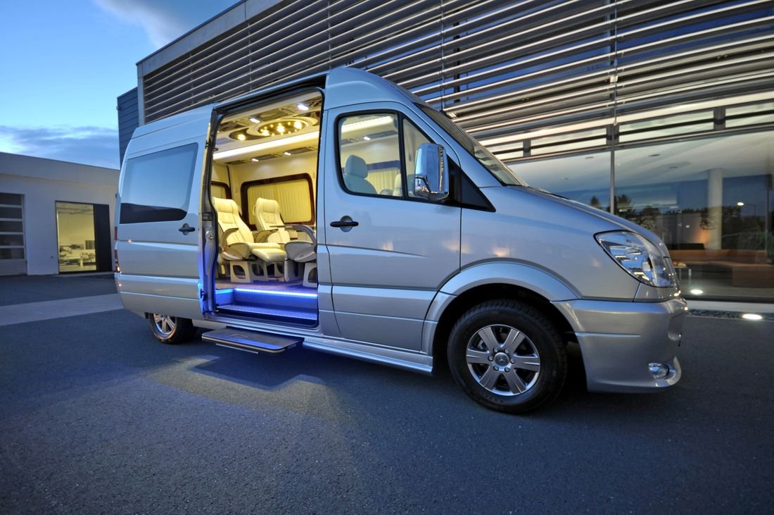 A VIP Mercedes Sprinter with its door open and the cabin lit at dusk